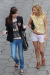 Moda uliczna w Mińsku. Upalny maj 2013 (ubrania i obraz: żakiet czarny, jeansy niebieskie, bluzka bez rękawów żółta, torebka czarna, szorty białe)