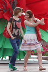Letnia moda uliczna 2013 w Mińsku (ubrania i obraz: top turkusowy, spódnica biała kwiecista, top z nadrukiem brązowy, torebka czerwona, jeansy niebieskie, trampki zielone)