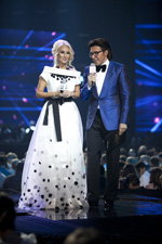 Lera Kudryavtseva and Andrey Malakhov. Show — Muz-TV Music Awards 2014. Evolution (looks: whiteevening dress, black belt, blond hair, blue blazer, white shirt, black bow-tie, black trousers)