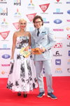 Lera Kudryavtseva y Andrey Malakhov. Ganadores y invitados — Premio Muz-TV 2015. Gravedad (looks: camisa blanca, corbata azul, zapatos de tacón azules, vestido de noche con flores blanco, traje de hombre azul claro)
