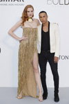 Alexina Graham and Olivier Rousteing. amfAR Cannes 2017 guests (looks: goldevening dress with slit, gold sandals, white blazer, black trousers)