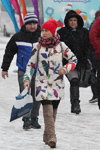 Moda uliczna pod śniegiem. Grudzień 2018 w Mińsku (ubrania i obraz: kozaki za kolano w kolorze kawa z mlekiem, palto z nadrukiem białe, dzianinowa czapka czerwona)