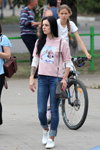 Sierpień 2018. Moda uliczna w Soligorsku (ubrania i obraz: bluza z kapturem różowa, jeansy niebieskie, buty sportowe białe, torebka szara)