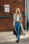 Street fashion. 08/2019 — Copenhagen Fashion Week SS2020 (looks: sky blue jeans, beige trench coat, black bag, white crop top, blond hair)