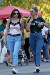 Straßenmode. 08/2019 (Looks: rosanes Top, schwarzer Gürtel, himmelblaue Jeans, Sonnenbrille, grünes Top mit Slogan, schwarzer Gürtel, blaue Jeans)