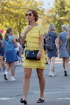 Moda uliczna. 08/2019 (ubrania i obraz: sukienka z falbanami żółta, sandały czarne, torebka czarna, okulary przeciwsłoneczne)