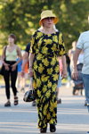 Moda uliczna. 08/2019 (ubrania i obraz: kapelusz żółty, sukienka kwiecista czarno-żółta, torebka czarna, sandały czarne)
