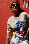 Kampania SiNSAY SS 2020 (ubrania i obraz: pulower z nadrukiem w kolorze kawa z mlekiem, jeansowe szorty białe, okulary przeciwsłoneczne)