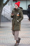 Moda en la calle en Minsk. 02/2020 (looks: gorro en punto fino con pompón rojo, abrigo kaki, pantalón gris, botines marrónes)