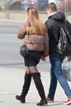 Moda uliczna w Mińsku. 03/2020 (ubrania i obraz: kozaki za kolano czarne, cienkie rajstopy czarne, skórzana spódnica mini czarna, kurtka w kolorze kawa z mlekiem pikowana)