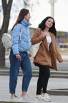 Straßenmode in Minsk. 03/2020 (Looks: himmelblaue gesteppte Jacke, blaue Jeans, graue Sneakers, weißer Rucksack, brauner Mantel, weißes Top, schwarze Jeans, weiße Sneakers)