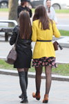 Straßenmode in Minsk. 04/2020 (Looks: schwarze Stiefel, schwarze Strumpfhose, schwarzes Kleid, gelber Mantel, schwarzes Kleid mit Blumendruck, schwarze Strumpfhose)