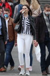 Moda en la calle en Minsk. 05/2020. Parte 4 (looks: cazadora de piel negra, blusa de rayas de color blanco y negro, vaquero blanco, bolso negro, sneakers grises)