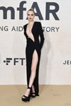Cara Delevingne. amfAR Gala Cannes 2022 (ubrania i obraz: suknia wieczorowa z rozcięciem z dekoltem czarna, sandały czarne, kok)