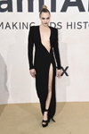 Cara Delevingne. amfAR Gala Cannes 2022 (ubrania i obraz: suknia wieczorowa z rozcięciem z dekoltem czarna, sandały czarne, kok)