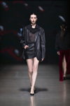 Pokaz NÓLÓ — Riga Fashion Week SS23 (ubrania i obraz: skórzana spódnica mini czarna, top czarny przejrzysty, półbuty czarne)