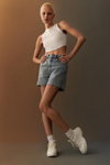 Kampania Primark SS 2022 (ubrania i obraz: krótki top biały, jeansowe szorty błękitne, skarpetki białe, buty sportowe białe, krótka fryzura)