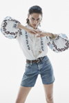 Kampagne von Replay SS 2022 (Looks: himmelblaue Jeans-Shorts, weiße Bluse mit Ornament-Muster)