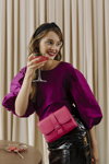 Party. Kampagne von Veritas 2022 (Looks: purpurrote Bluse, himbeerfarbene Handtasche, schwarzer Mini Lederrock)