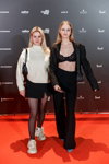 Goście — Riga Fashion Week SS24 (ubrania i obraz: pulower biały, spódnica mini czarna, rajstopy czarne, buty sportowe białe, blond (kolor włosów), torebka czarna, spodnium czarne, biustonosz czarny, półbuty błękitne)