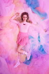 Camille Dhont. Kampagne von CAMILLE x JBC (Looks: rosaner Pullover, rosaner Mini Rock, weiße Socken, weiße Sneakers)