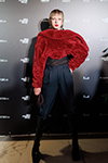 Goście — Riga Fashion Week AW24/25 (ubrania i obraz: pulower futrzany bordowy, spodnie czarne, kozaki czarne)