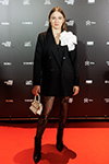 Goście — Riga Fashion Week AW24/25 (ubrania i obraz: żakiet czarny, botki czarne, ażurowy rajstopy czarne, torebka biała)